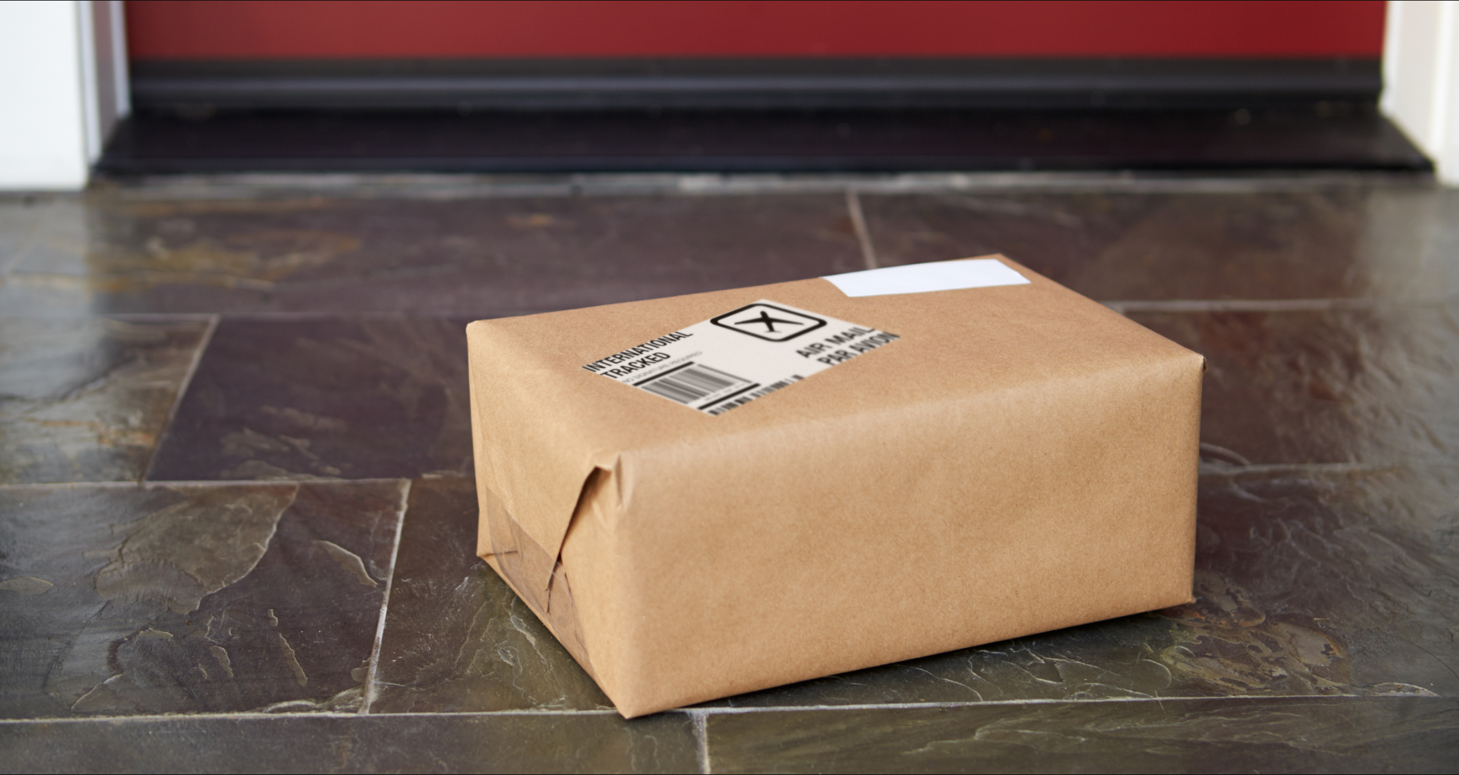 Medium size package wrapped in brown paper sitting on a doorstep